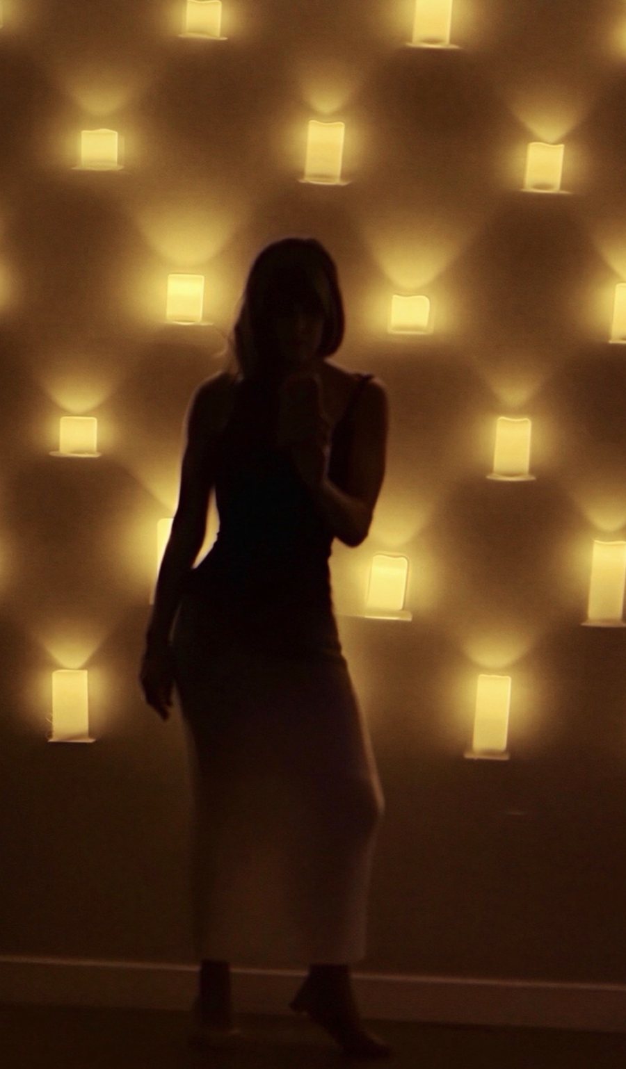 Armanda silhouetted against the candle wall